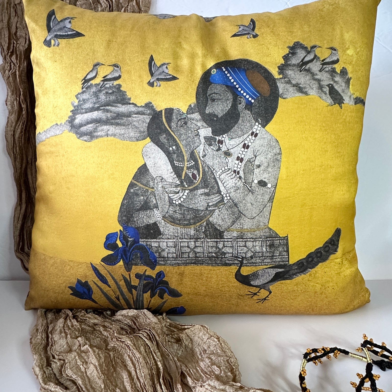 An 18x18 miniature art cushion cover by Sumaira Tazeen featuring a royal Mughal couple portrait on a shimmering gold background with blue floral accents.