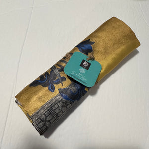 A rolled gold miniature art cushion cover by Sumaira Tazeen, highlighting the premium fabric texture and authentic  artist studio tag.