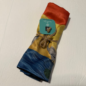 A packaged Mughal art cushion cover showing the detailed blue water and red sky motifs, tied with jute string and a Sumaira Tazeen artist studio tag.
