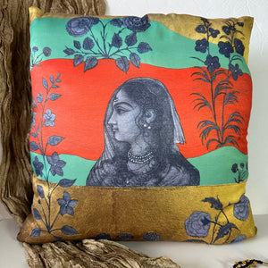 An 18x18 original artwork print cushion cover by Sumaira Tazeen featuring a profile portrait of a Mughal Rani (Queen) against a warm orange, red, and gold-toned landscape.