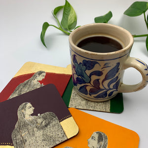 Close-up of a blue patterned coffee mug sitting on a forest green hand-painted coaster, styled as statement decor for a creative space.