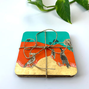 A stack of hand-painted coasters tied with a rustic twine bow, showing the orange landscape and bird artwork on the top piece.