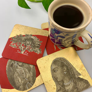 A lifestyle shot of a patterned ceramic mug sitting on stacked chai coffee coasters, highlighting the royal bright red aesthetic and gold leaf accents.