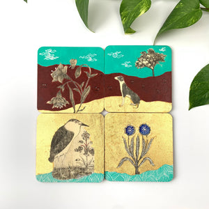 A set of 4 hand-painted coasters featuring Mughal miniature art motifs including flowers, a dog, and a bird on gold and turquoise backgrounds.