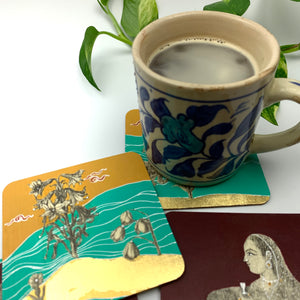 Set against a collection of hand-painted coasters, a blue-and-white floral mug rests on a teal design highlighted with floral accents, while the remaining coasters feature regal portraits and gold leaf detailing.