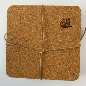 The underside view of a hand-painted coaster revealing the soft cork sheet backing designed to prevent surface damage and table slipping.