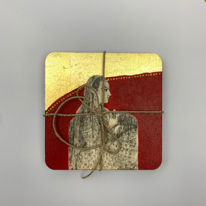 Top-down view of a hand-painted coaster featuring a female portrait on a crimson backdrop with a large gold leaf section at the top.
