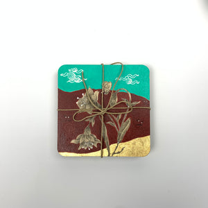Front view of a stack of hand-painted coasters tied with twine, featuring the floral motif and signature gold detailing.