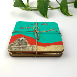 A side view of artisan tabletop decor showing four hand-painted coasters stacked and tied with a rustic jute string, ideal for unique wedding, housewarming or anniversary gifts.