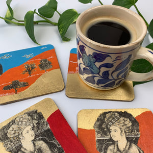 A blue patterned ceramic mug sitting on a gold-leaf landscape coaster, surrounded by other coasters featuring Persian Prince South Asian miniature art.