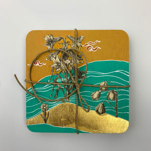 Top-down view of a hand-painted coaster tied with string, featuring a  floral design on a teal and mustard yellow background.