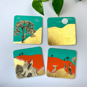 Four hand-painted coasters displayed on a white surface, showing nature themes with gold leaf gilding.