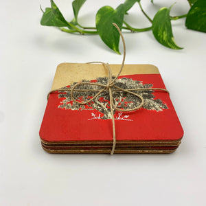 A side-angle view of four hand-painted coasters stacked and tied with rustic jute twine, emphasizing the thick plywood layers and gold leaf finish.