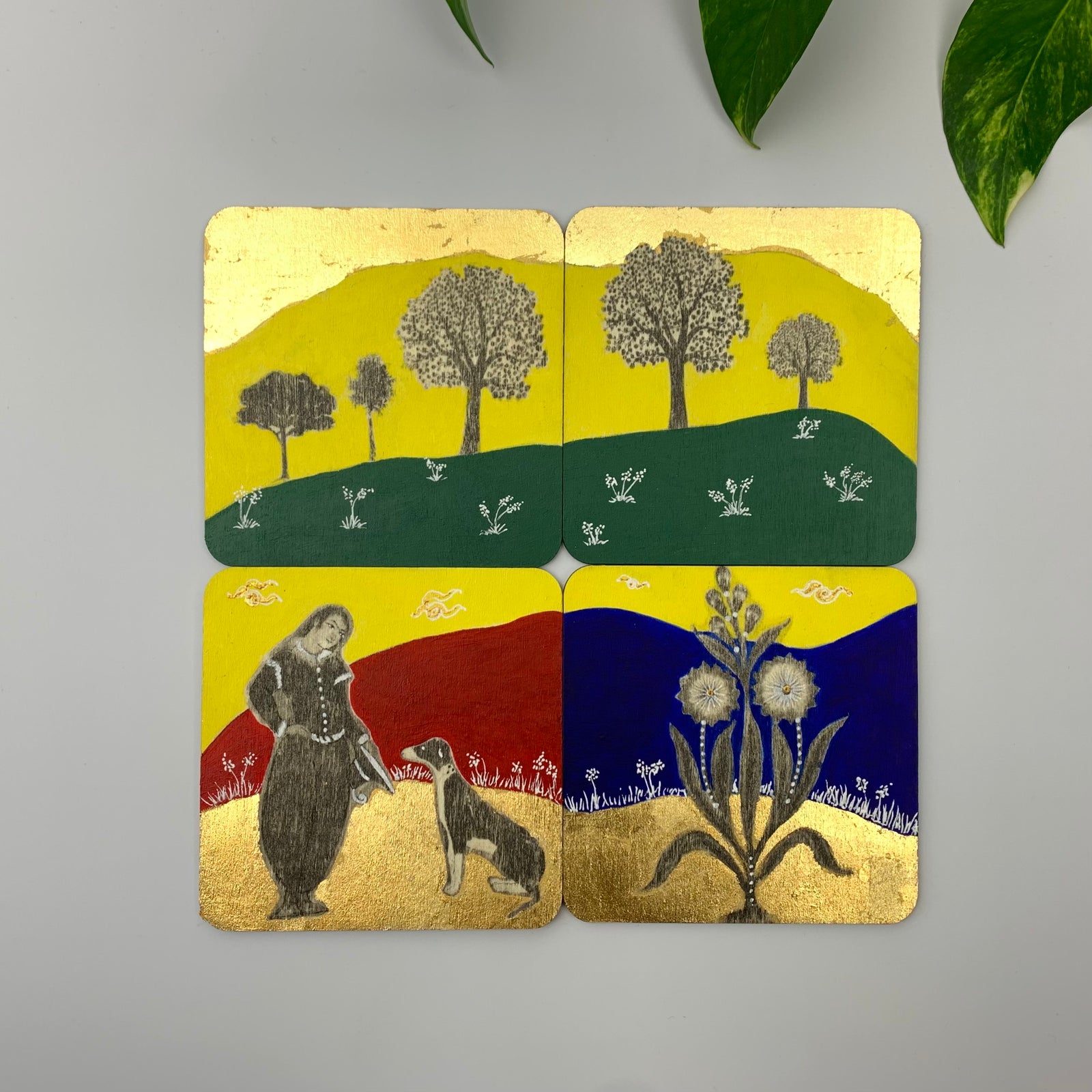 A grid of four hand-painted coasters showcasing a garden scene with royal figures, tall trees on green hills, and botanical flowers.